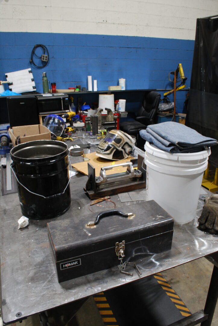 Cluttered workshop table with toolbox and buckets