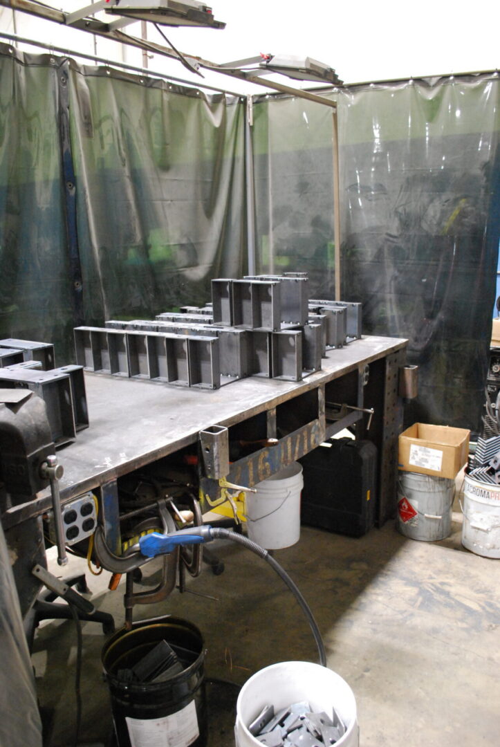 Metal fabrication workspace with parts on workbench